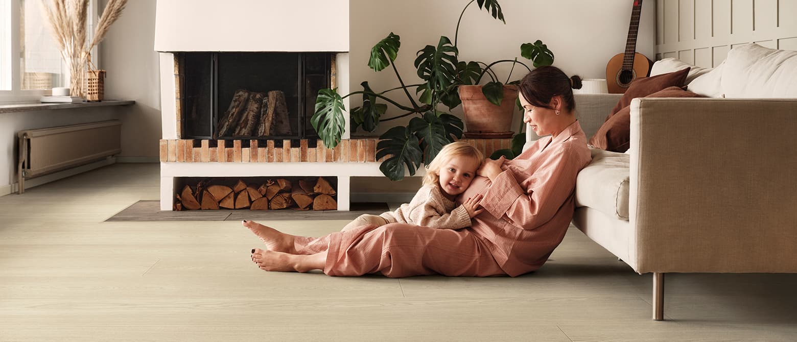 pregnant woman and daughter sitting on a beige laminate floor in a living room